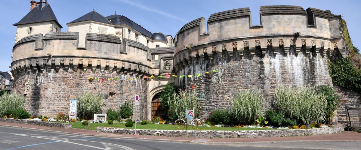 A historic castle with round towers and a stone wall.