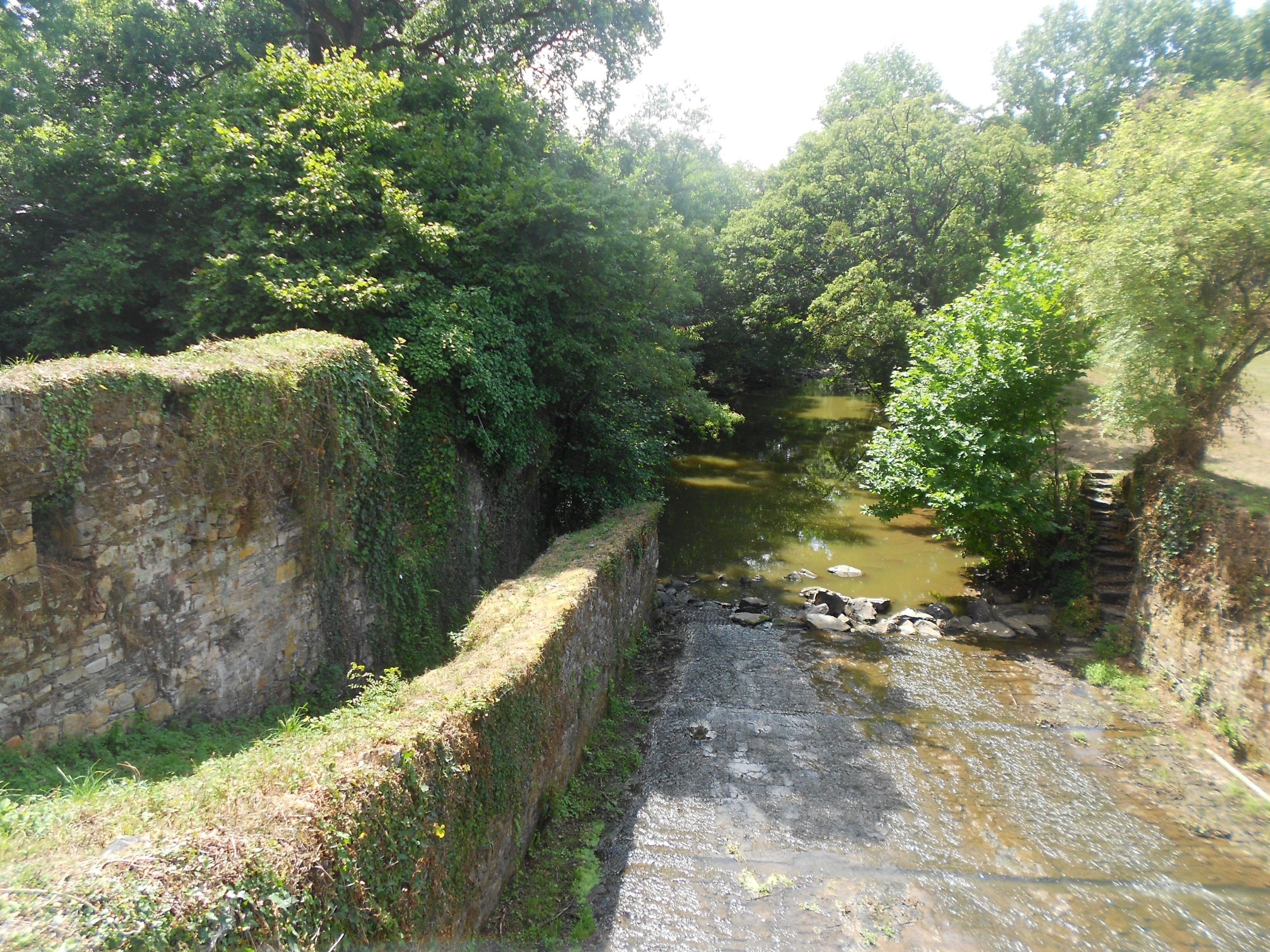 A narrow, rocky waterway flanked by stone walls and lush greenery.