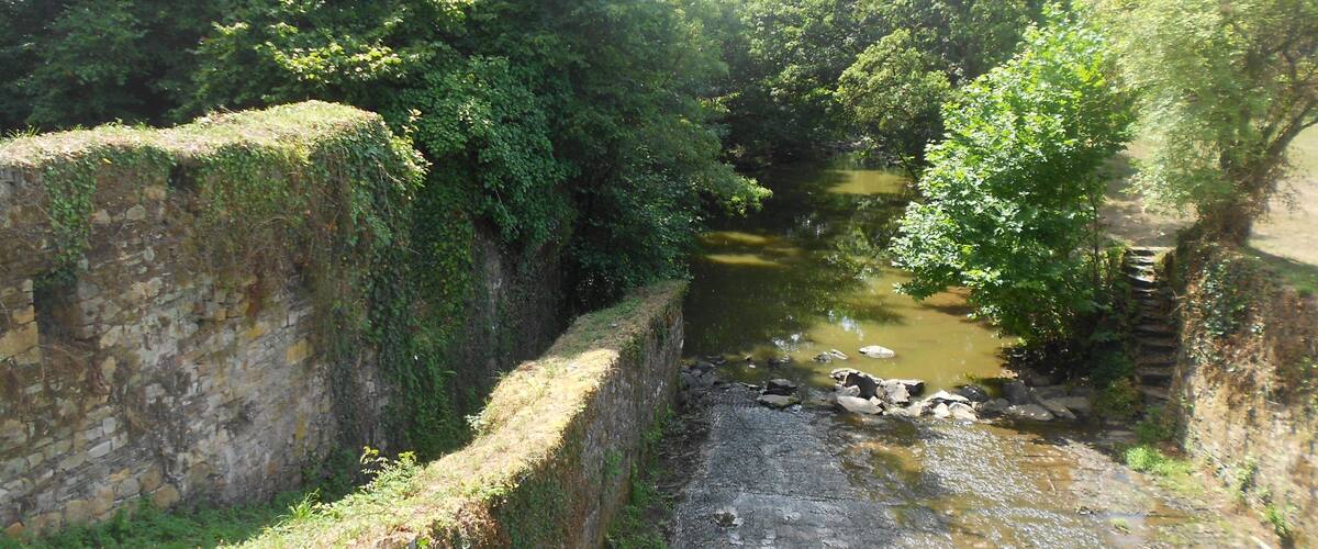 A narrow, rocky waterway flanked by stone walls and lush greenery.