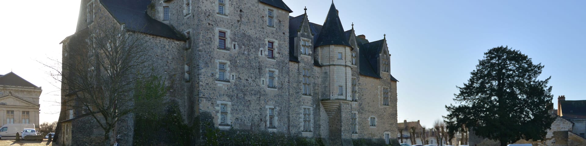 A historic castle with a well-maintained garden and a clear sky.