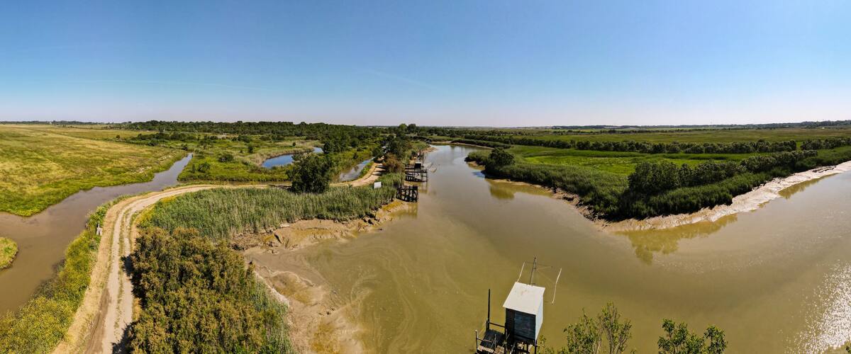 A river meandering through a green landscape with a bridge and a small structure near the water.