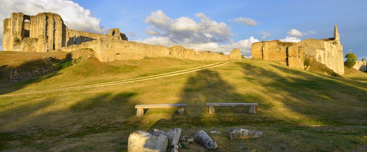 An ancient stone castle with ruins, a grassy hill, and a clear sky.