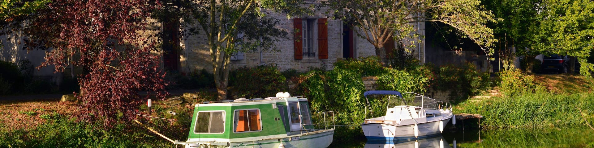 Panoramique deux bateaux sur la Sèvre Nortaise au soleil couchant à Damvix (85420), département de Vendée en région Pays de la Loire, France