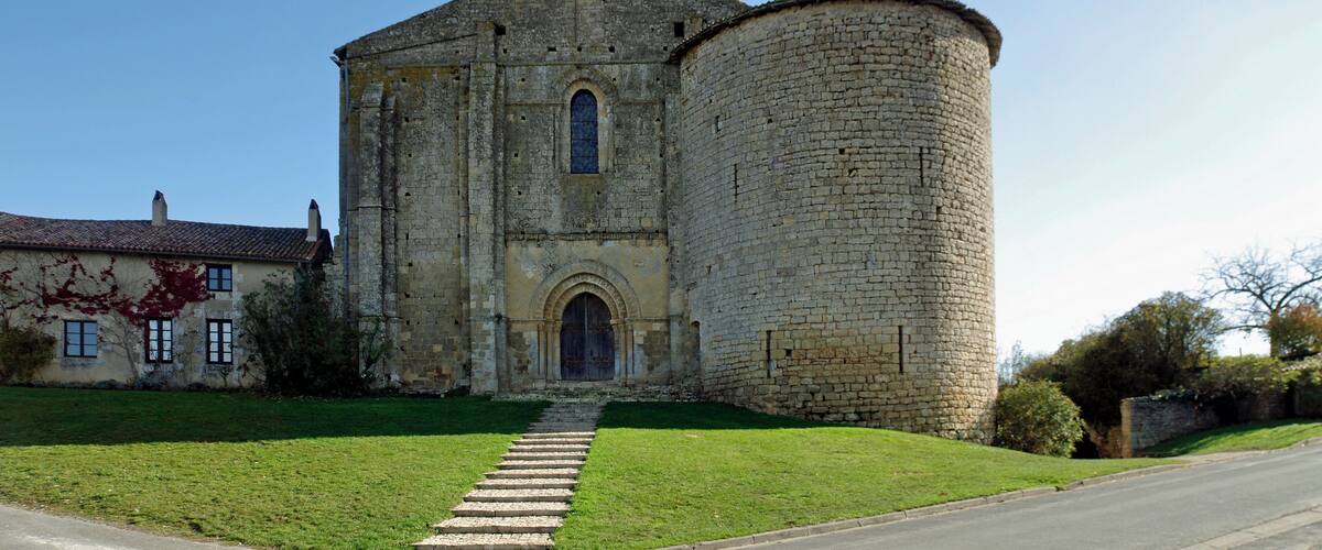 A historic stone church with a bell tower and a round tower.