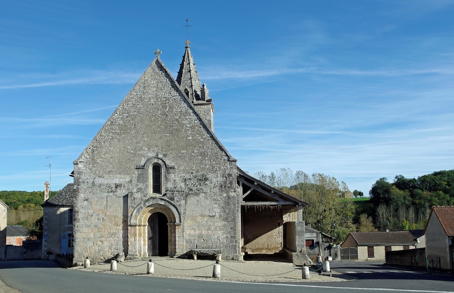 A stone church with a pointed roof and a cross on top.