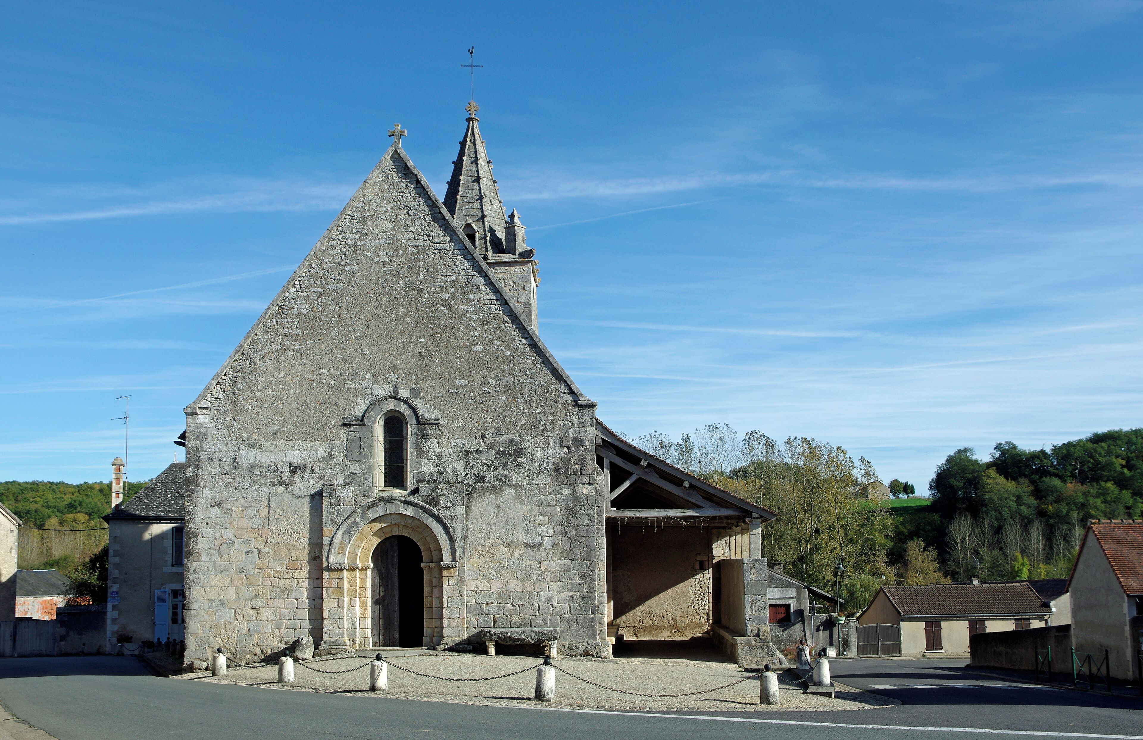 A stone church with a pointed roof and a cross on top.