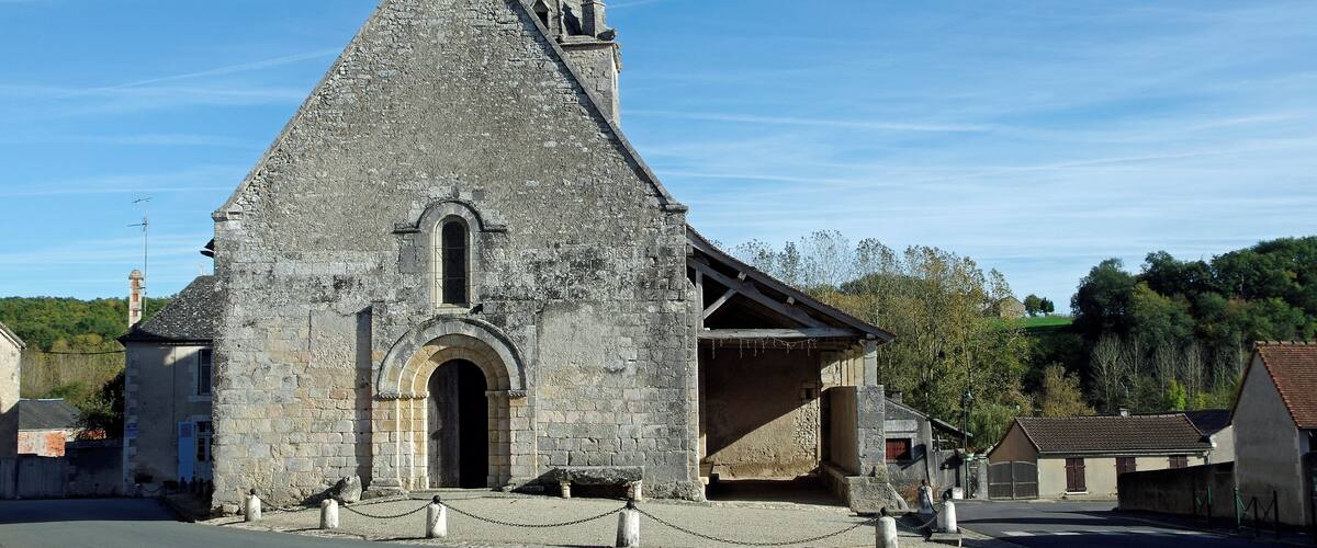 A stone church with a pointed roof and a cross on top.