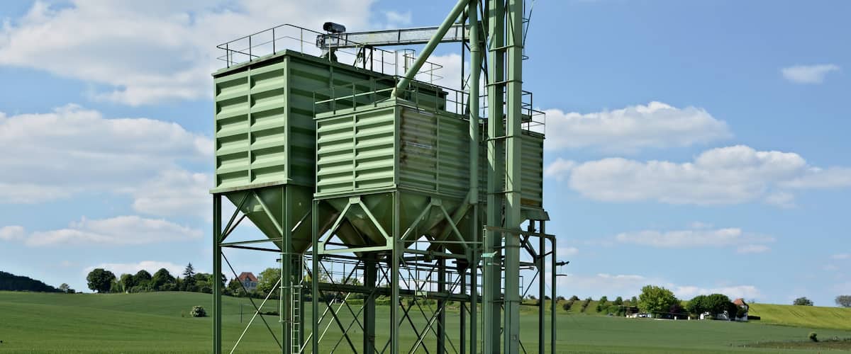 A large green industrial structure in a rural landscape with a clear sky.