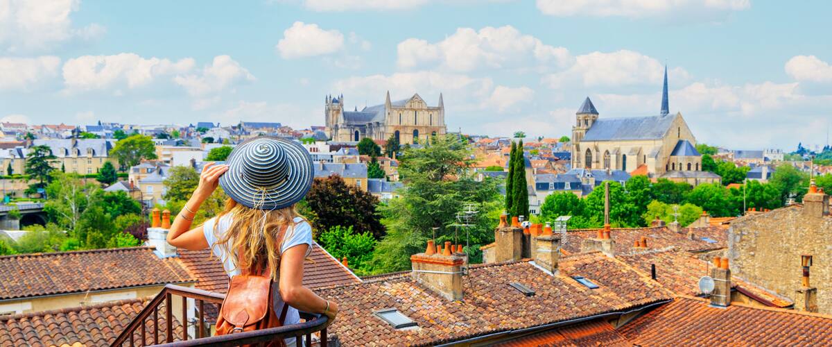 A woman with a striped hat overlooking a cityscape with historic buildings and a church.