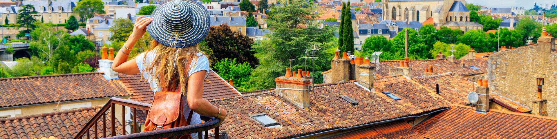 A woman with a striped hat overlooking a cityscape with historic buildings and a church.