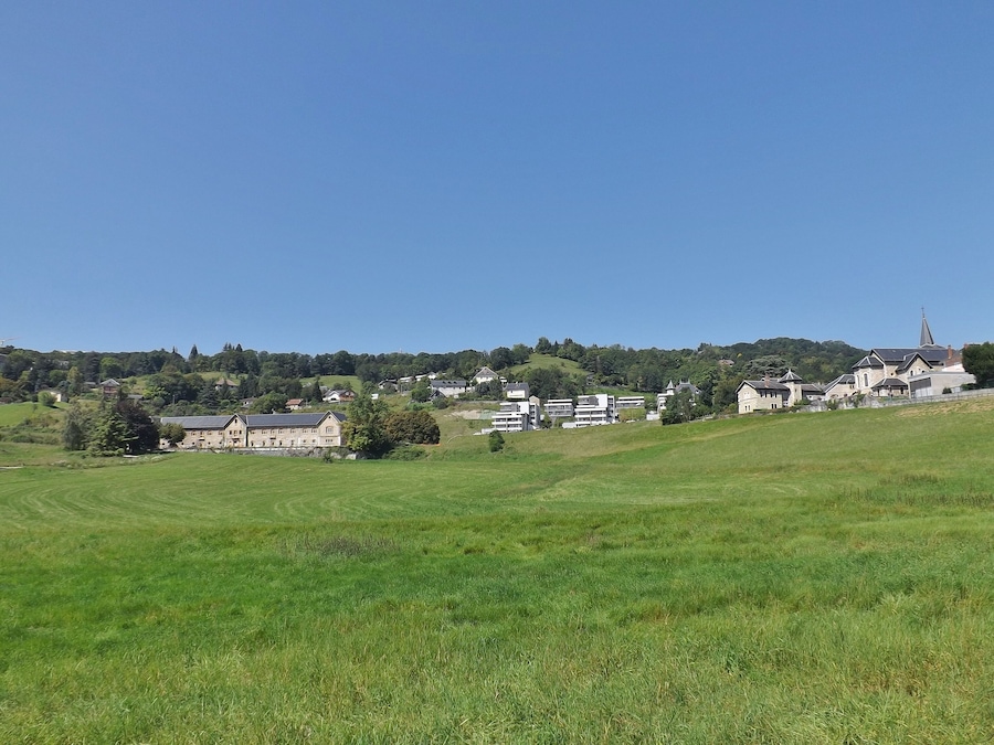 A rural landscape with rolling hills, a church, and residential buildings.