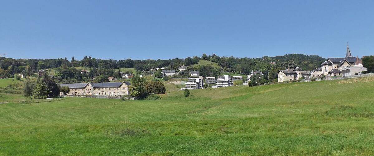 A rural landscape with rolling hills, a church, and residential buildings.