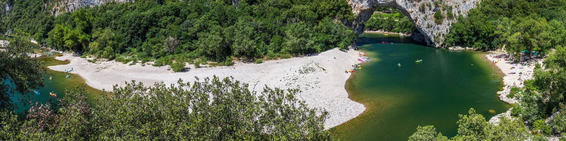 Un paisaje costero con una formación rocosa destacada y un arco natural sobre una bahía tranquila.