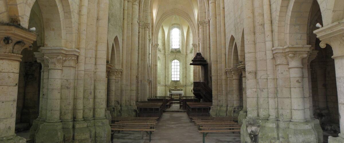 An interior of a cathedral with high arched ceilings, stone columns, and wooden pews.