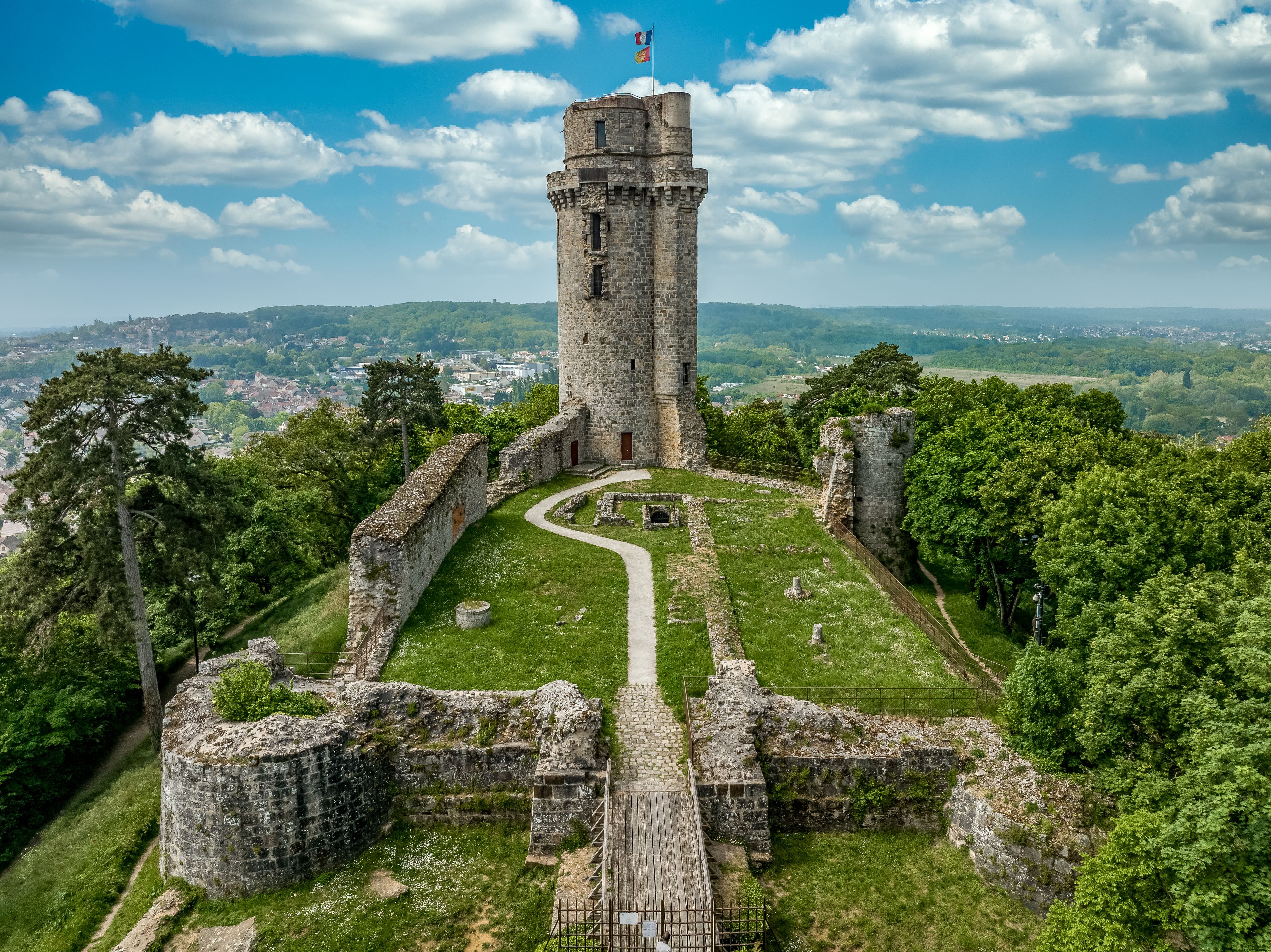 Een historische stenen toren, omringd door weelderige begroeiing en een kronkelend pad.