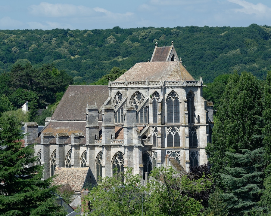 A historic cathedral with Gothic architecture, surrounded by lush green hills.