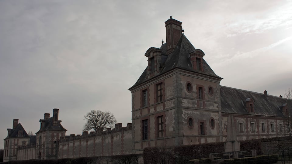 A large, historic building with multiple chimneys and a prominent tower.