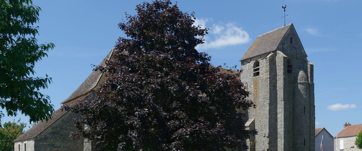 A stone church with a bell tower, surrounded by a grassy area and trees.