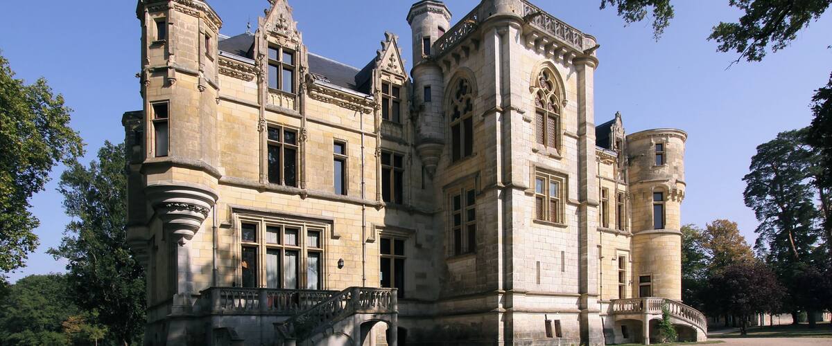 A large, historic stone building with ornate architecture, including turrets and a grand staircase.