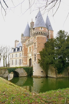 Un castillo histórico con varias torres, un foso y un puente.