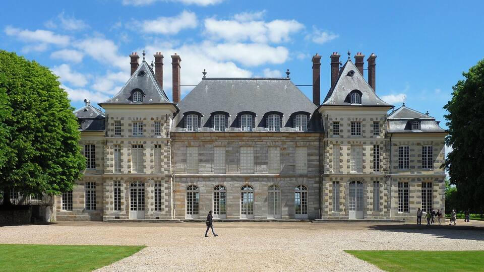 A large historic building with multiple chimneys and arched windows.