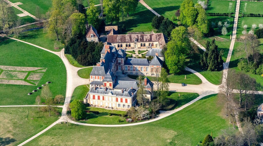An aerial view of a large estate with a prominent building, surrounded by well-maintained gardens and open fields.