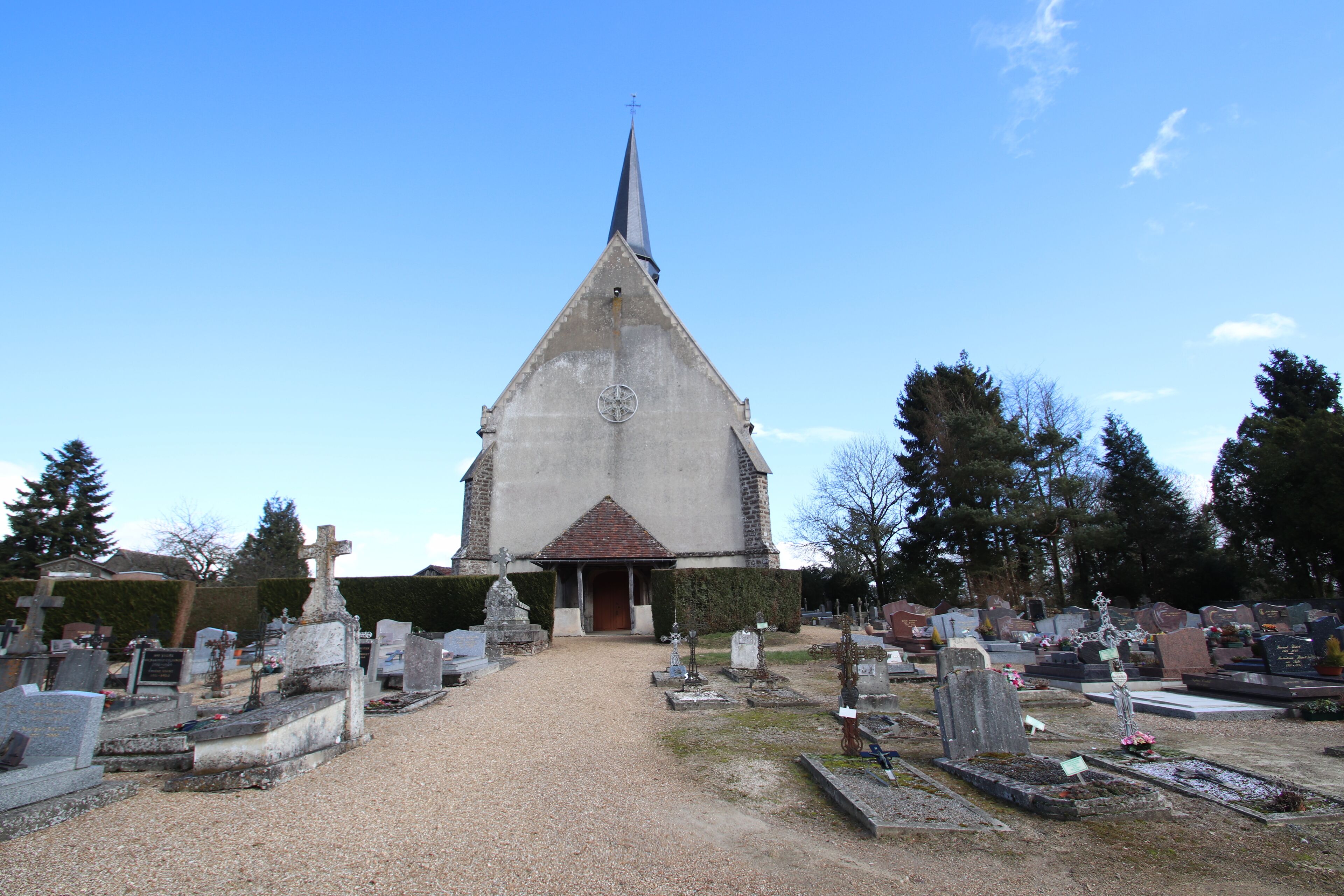 A church with a tall steeple and a graveyard in front.