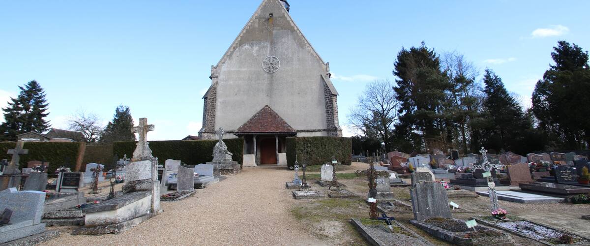 A church with a tall steeple and a graveyard in front.