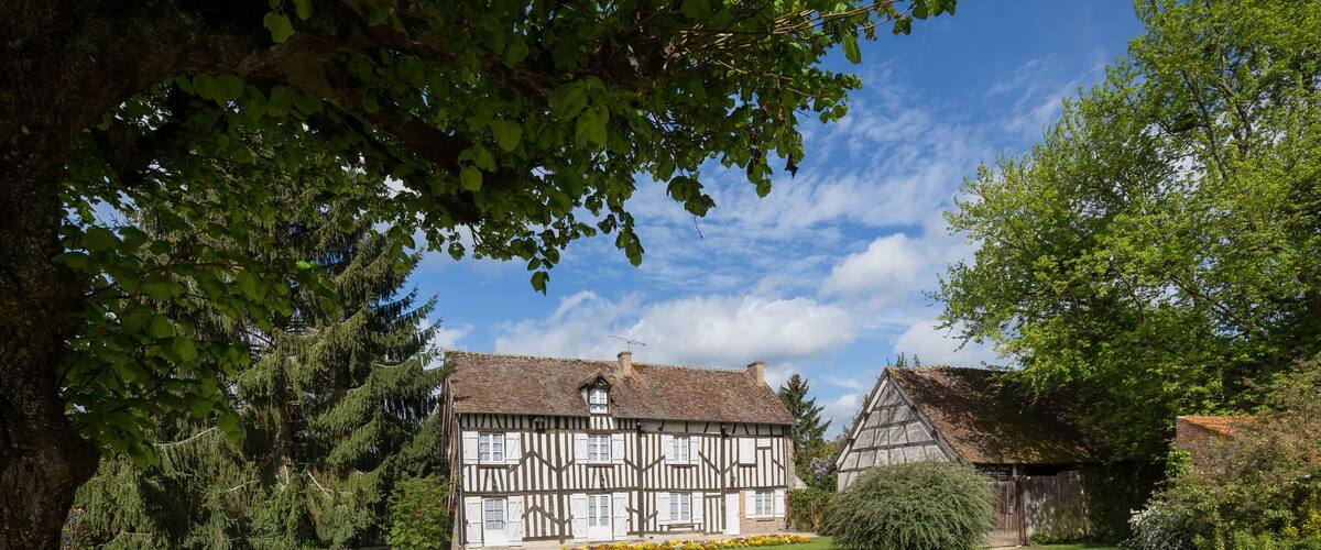 A traditional half-timbered house with a well-maintained lawn and a gravel path leading to it.