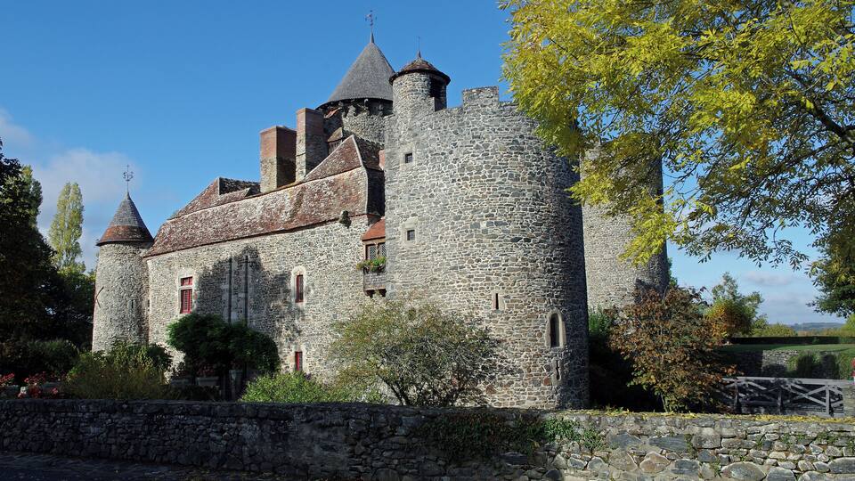 A historic stone castle with multiple towers and a red-tiled roof.