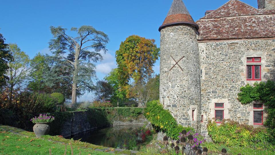 A stone tower with a conical roof, a small pond, and surrounding greenery.