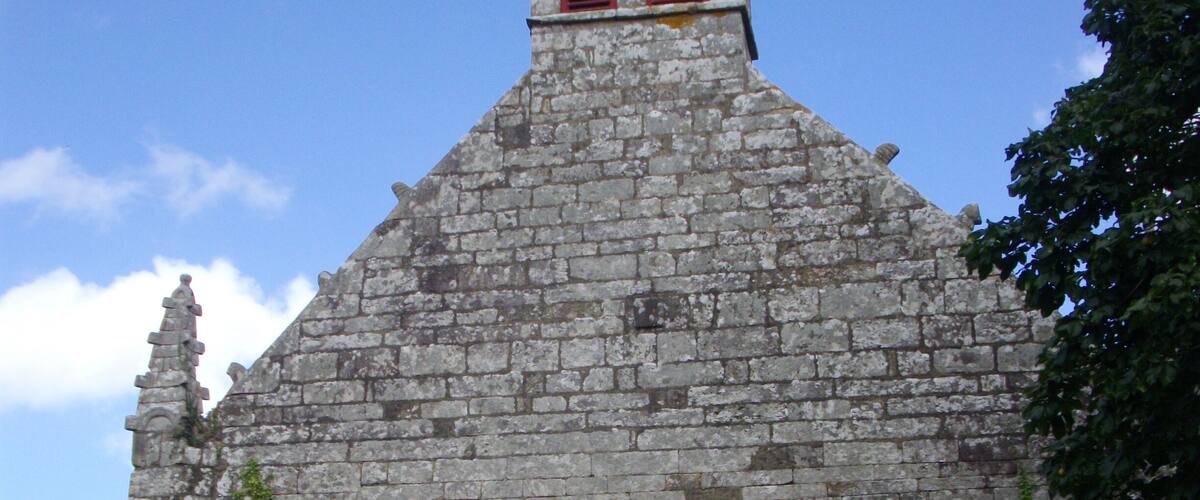 A stone church with a wooden door and red shutters.