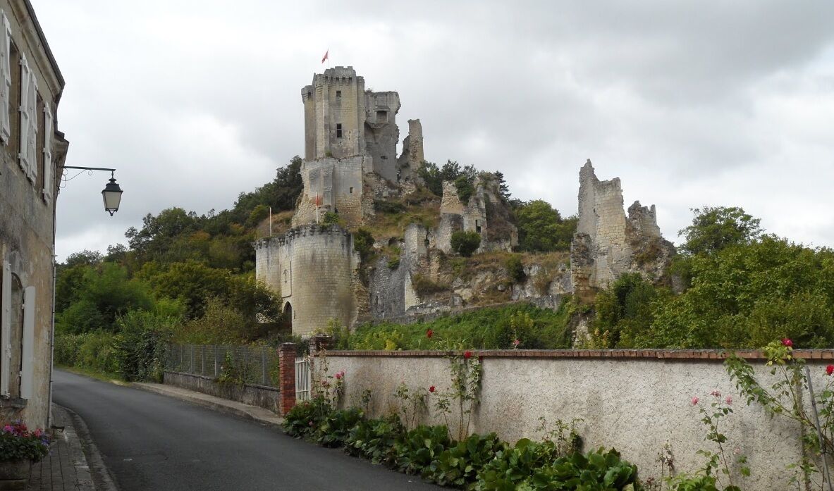 A historic castle ruin on a hill with a street in the foreground.