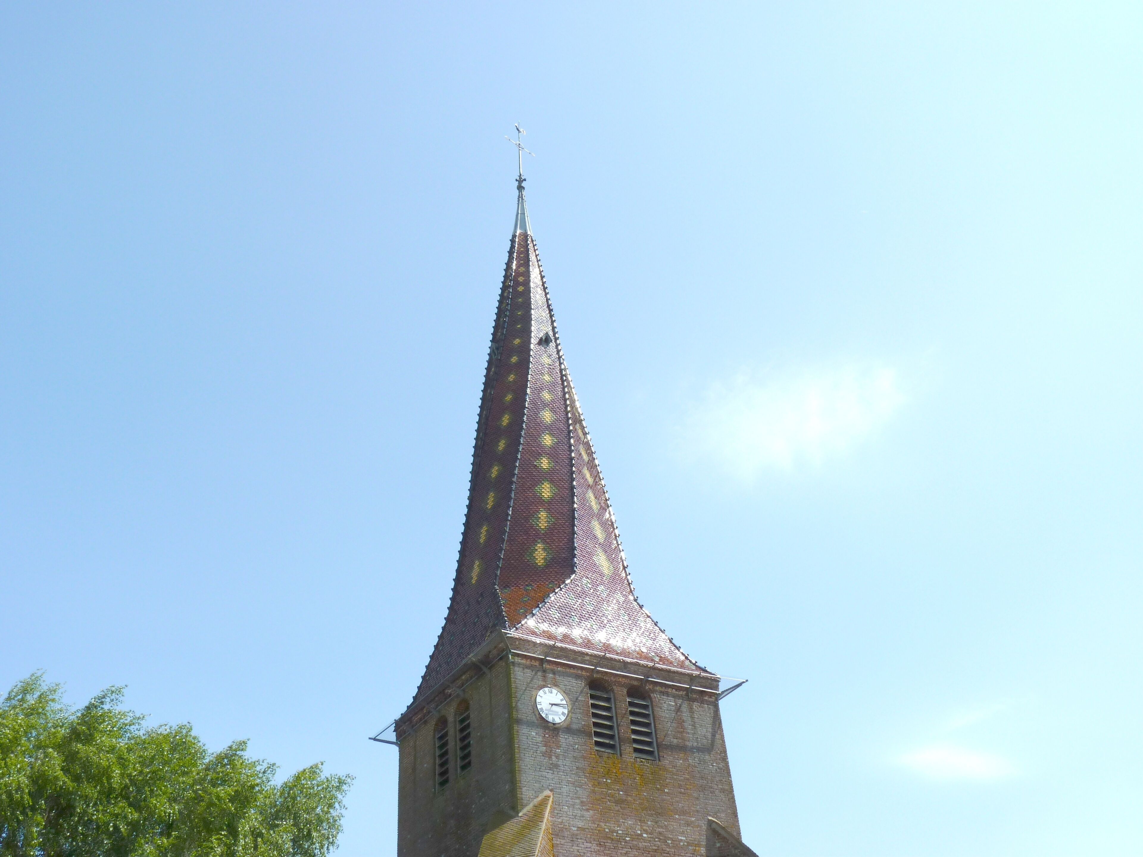 A church tower with a pointed roof and a clock.