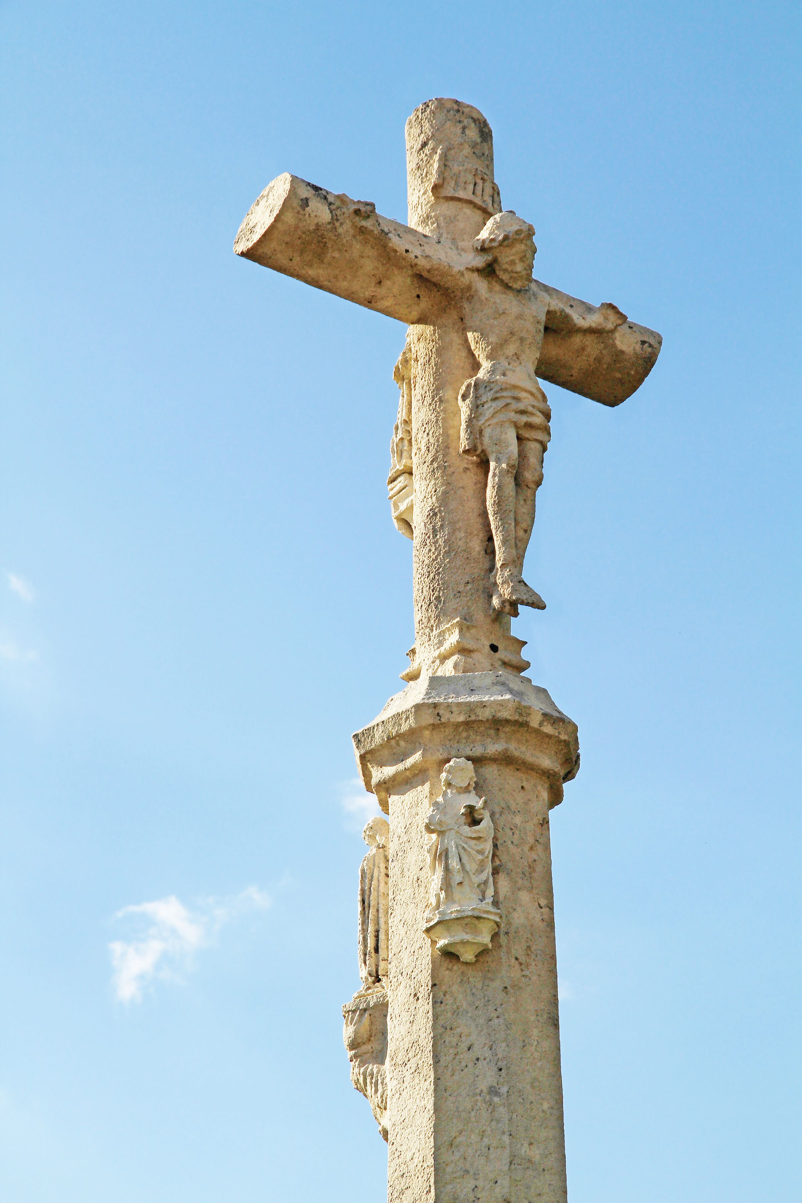 A stone cross with a figure of Jesus Christ on it.
