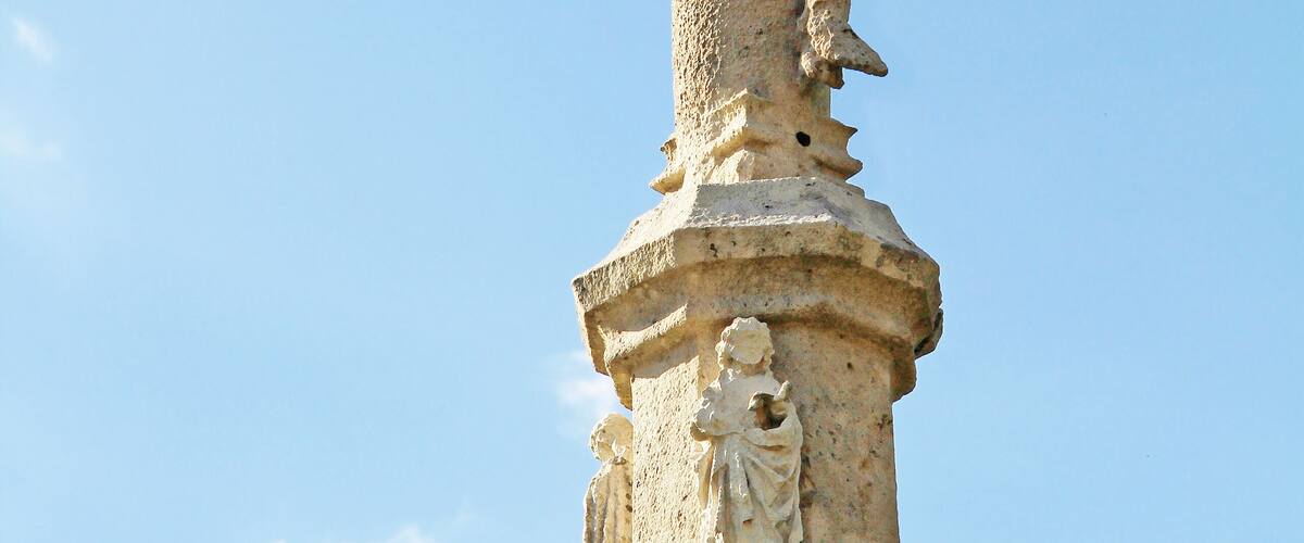 A stone cross with a figure of Jesus Christ on it.