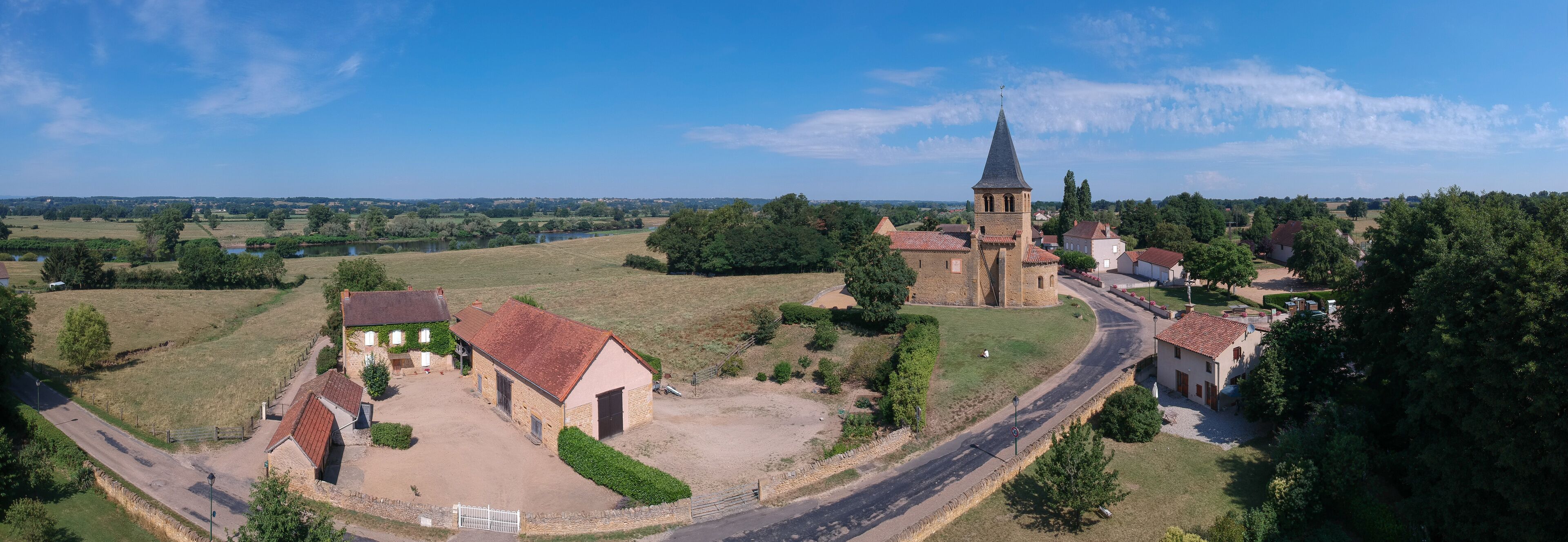 A rural village with a church, stone buildings, and a river in the background.