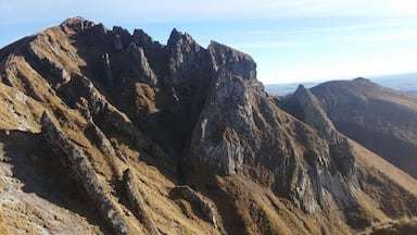 Les orgues basaltiques plissés (pans de roche verticaux, semblables à des tuyaux d'orgue) sont la trace d'un ancien lac de lave solidifié, comme indiqué par les panneaux descriptif du paysage présents sur place. Photo prise depuis le Col de Coure.