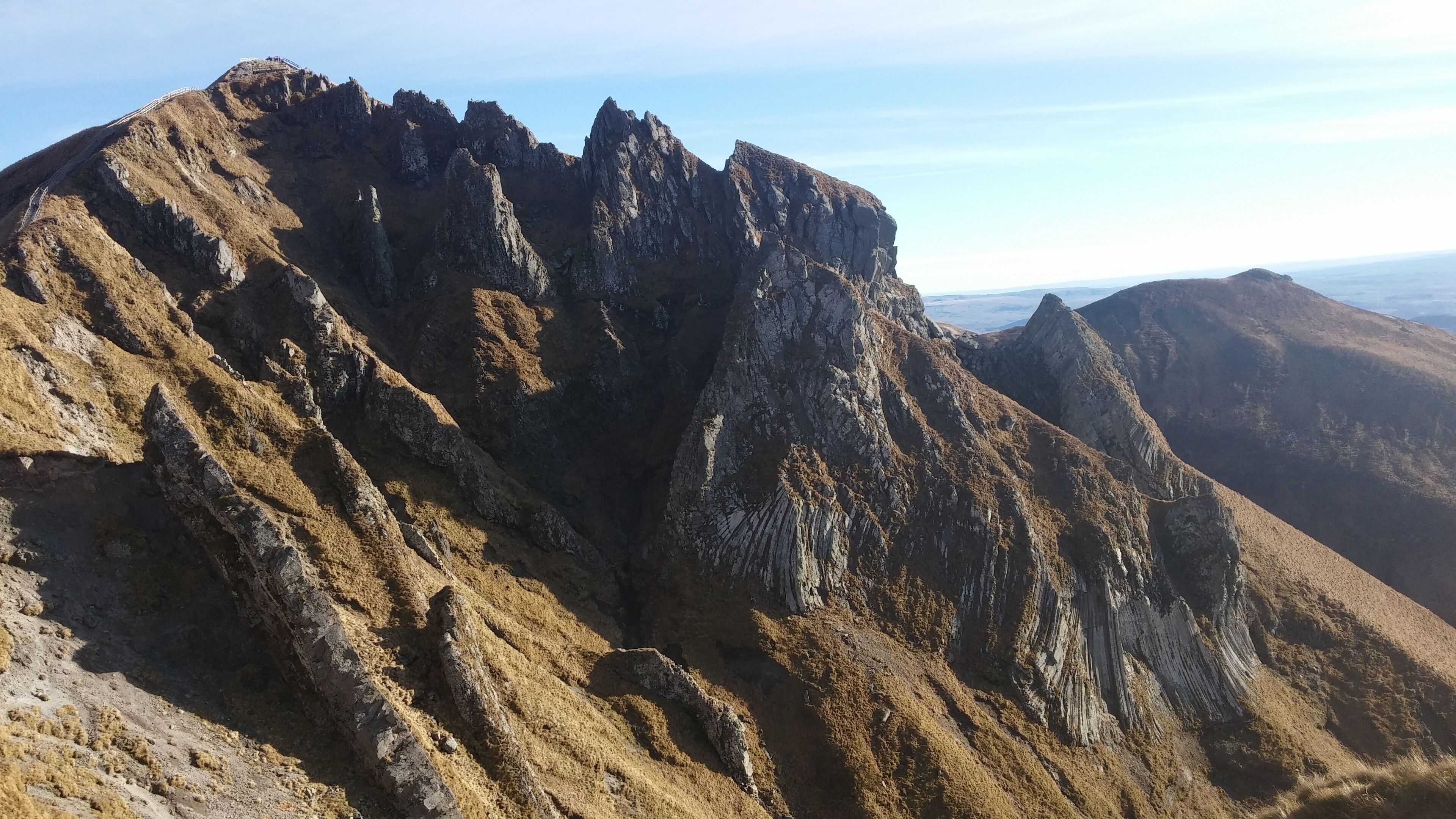 A rugged mountain peak with steep, rocky slopes and a clear sky.