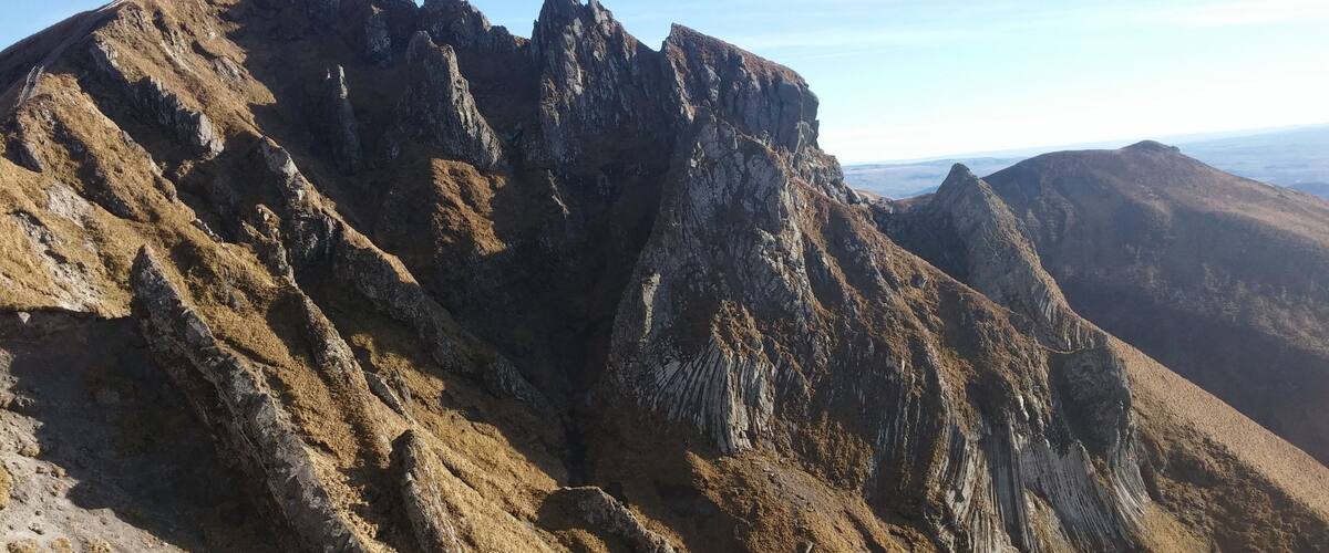 A rugged mountain peak with steep, rocky slopes and a clear sky.