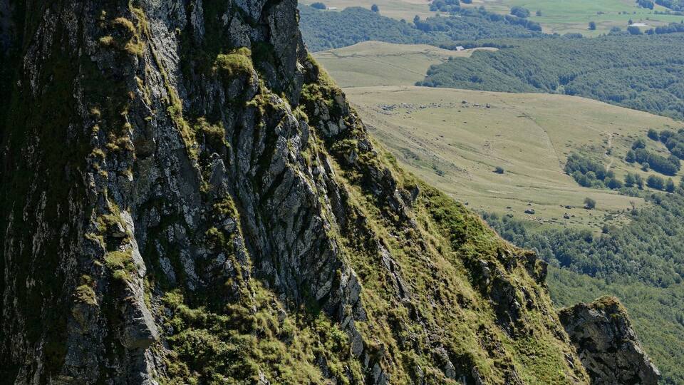 A rugged mountain peak with steep, rocky slopes and patches of green vegetation.