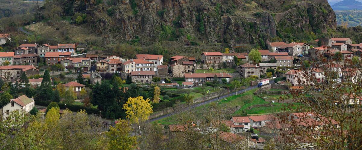 A historic castle on a hill overlooking a town with red-roofed houses.
