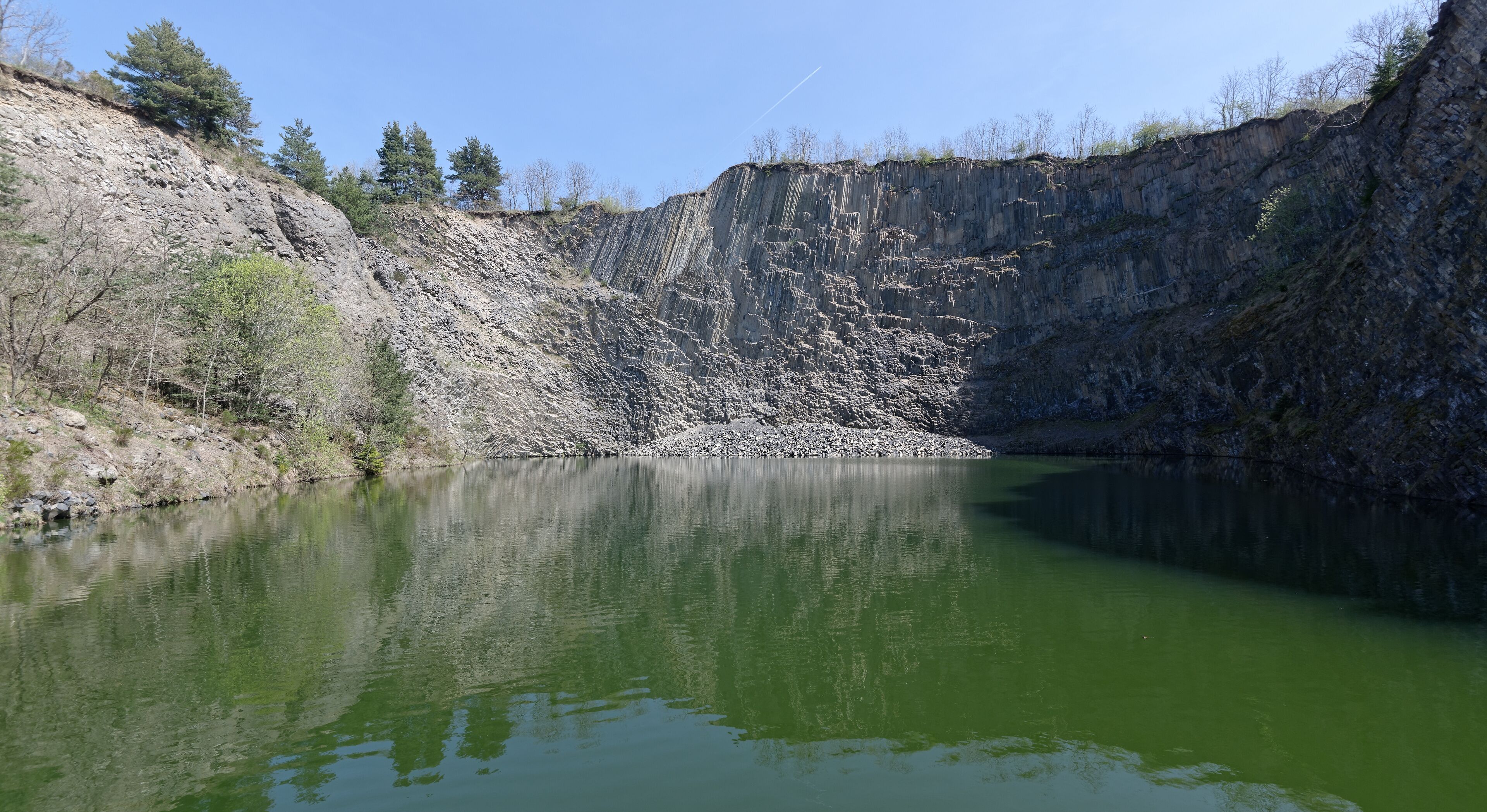 A calm lake surrounded by rocky cliffs and sparse trees.
