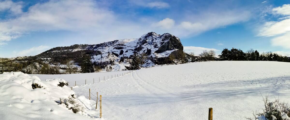 A snow-covered landscape with a prominent mountain and a fenced area.
