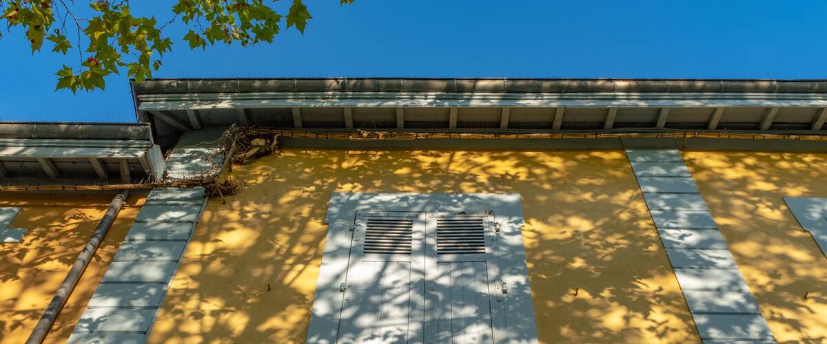 A building with the sign "ECOLE DE FILLES" and a window with shutters.