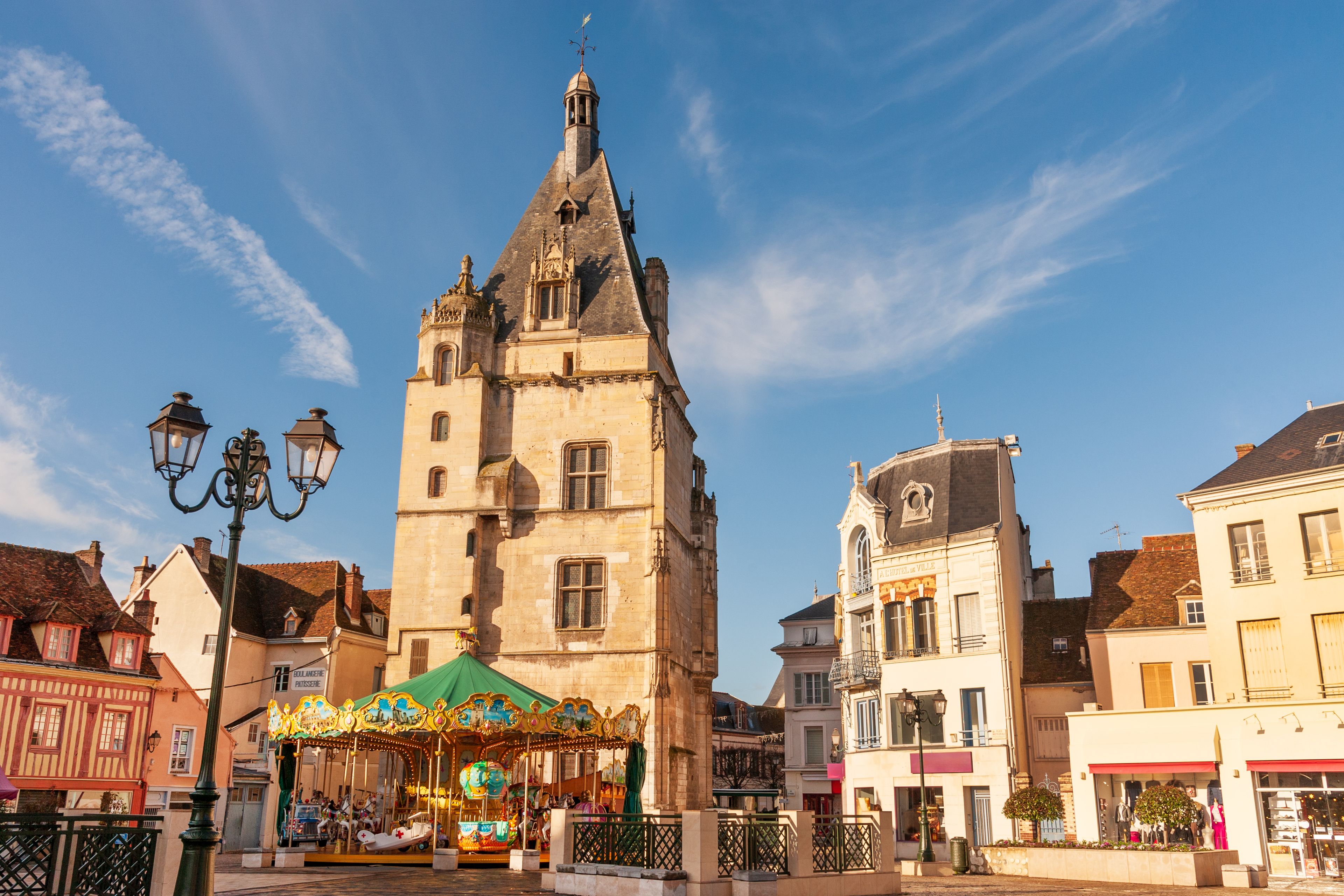 Een historische toren met een klok, een draaimolen en typisch Europese architectuur.
