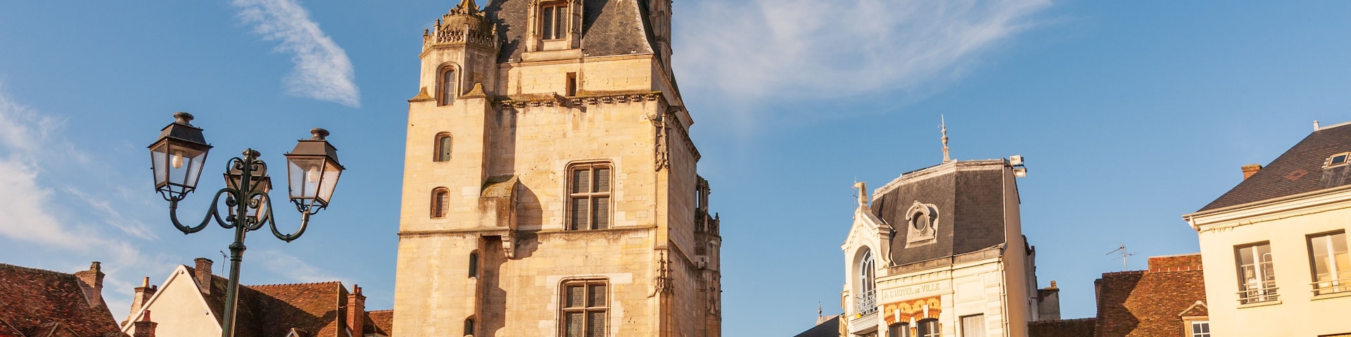 Uma torre histórica com relógio, carrossel e arquitetura europeia tradicional.