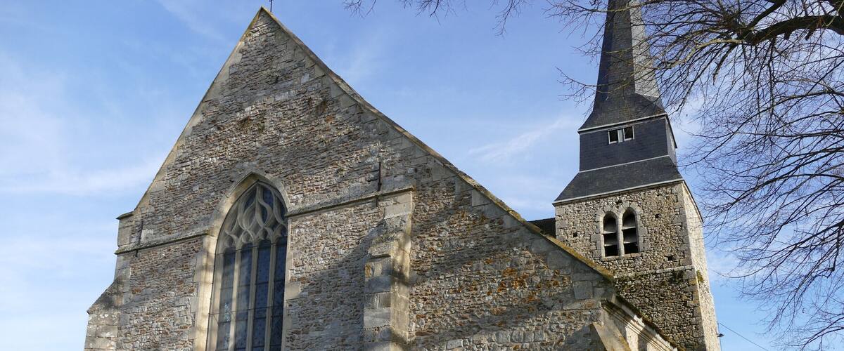 A stone church with a tall steeple and a large arched window.
