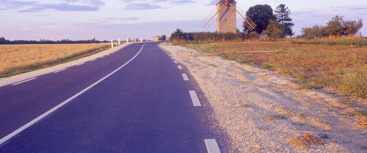 A road leading to a windmill in a rural landscape.