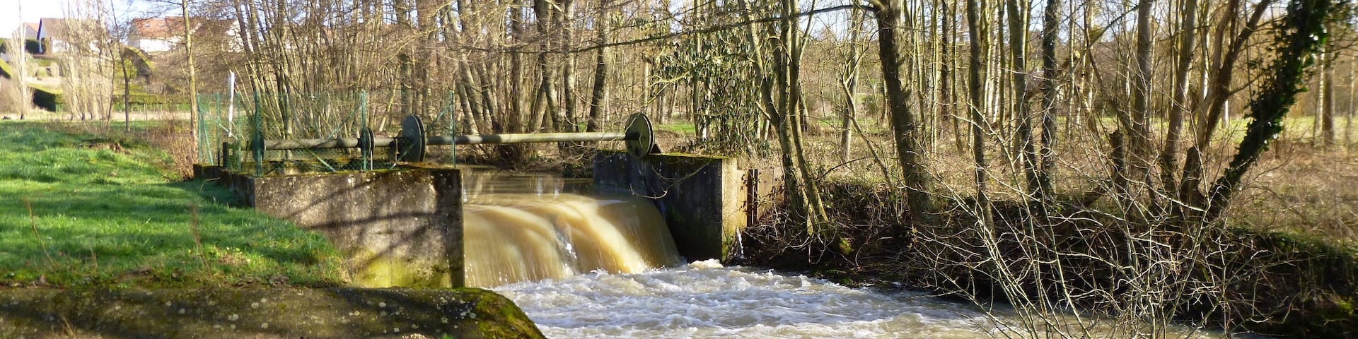 La Chapelle-sur-Aveyron, Loiret, Centre, France. Communal pond, south-east side. The Aveyron river, near the communal pond. The pond's overflow runs over the path which goes around the pond, to join with the Aveyron river just after a weir.